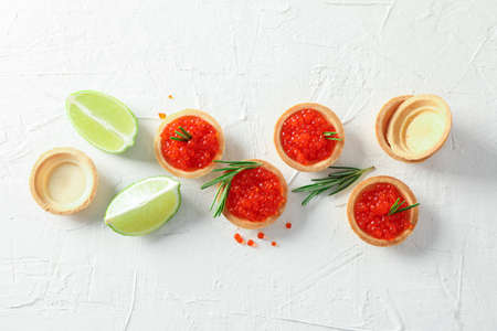 Flat lay composition with tartlets with caviar, rosemary and limes on white backgroundの写真素材