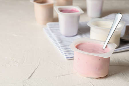 Composition with plastic cups with yogurt on white tableの写真素材