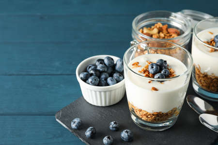 Composition with parfaits desserts on blue wooden background, space for text