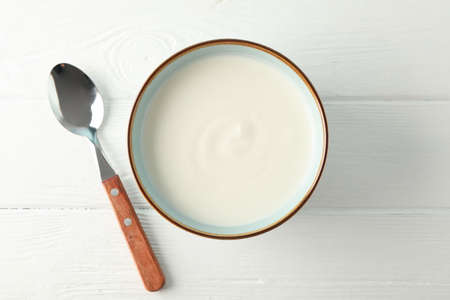 Bowl of sour cream yogurt with spoon on white backgroundの写真素材