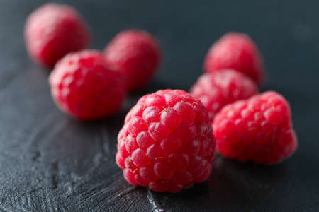 Raspberries on black cement background, closeup and space for text