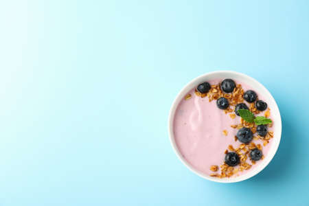 Yogurt with granola, blueberry and mint on color backgroundの写真素材