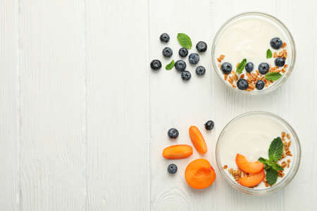 Flat lay composition with yogurt desserts and ingredients on white wooden backgroundの写真素材