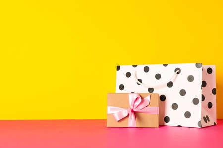 Paper bag with present on multicolor background, space for textの写真素材
