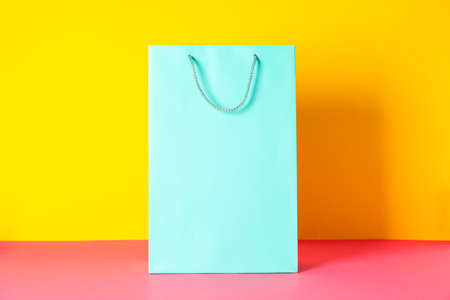 Color paper bag on pink table against yellow background, copy spaceの写真素材