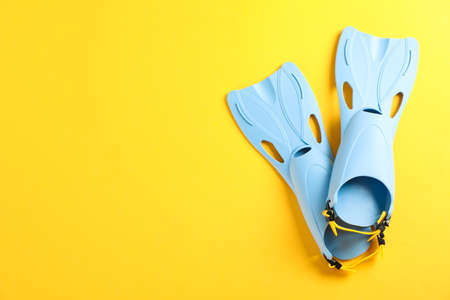 Pair of blue flippers on yellow background, space for textの写真素材