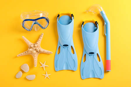 Flippers, snorkel, diving mask and starfishes on yellow background, space for textの写真素材