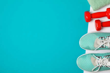 Flat lay composition with dumbbells, towel and sneakers on color background