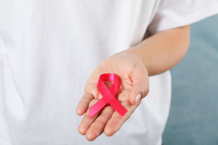 Girl in t-shirt hold awareness ribbon against blue backgroundの写真素材