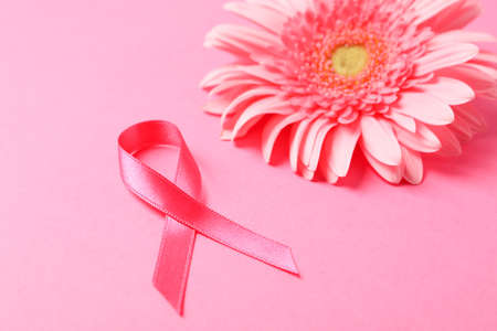 Pink awareness ribbon and gerbera on color background, space for text.の写真素材