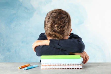 Boy sleeps on notebooks heap against color background, space for textの写真素材