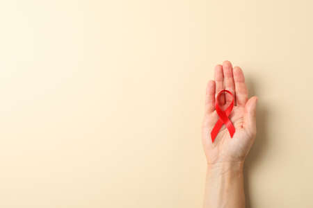 Female hand hold red awareness ribbon on color background, space for textの写真素材