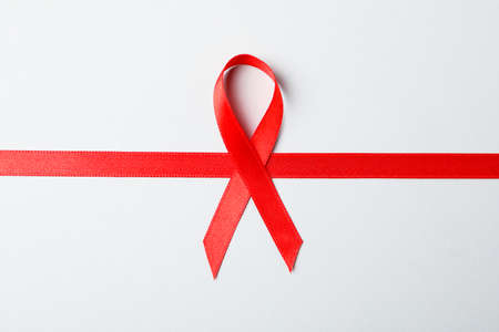 Red awareness ribbon on red background, space for textの写真素材