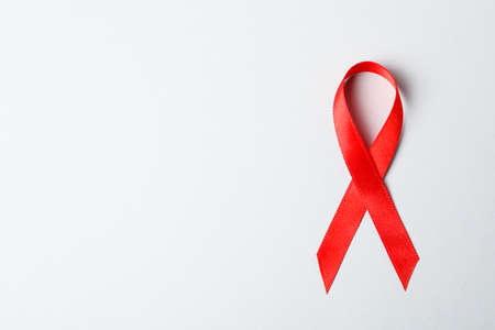 Red awareness ribbon on red background, space for textの写真素材