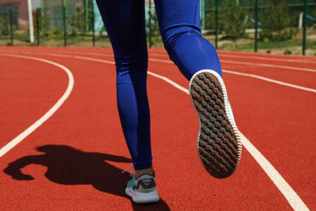 Girl running on red athletic track. Sport conceptの写真素材
