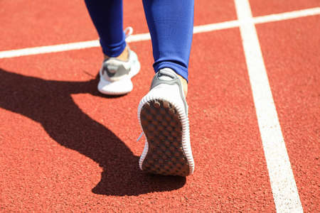 Girl walking on red athletic track, close up