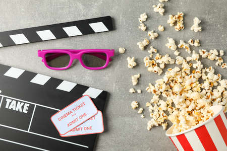 Clapperboard, tickets, 3d glasses and bucket with popcorn on grey background, top viewの写真素材