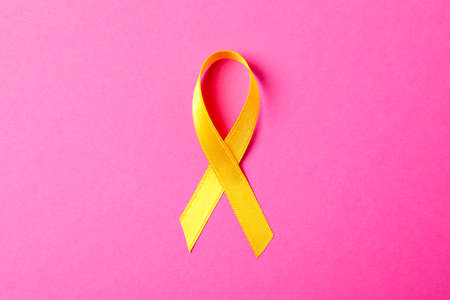 Yellow awareness ribbon on pink background, space for textの写真素材