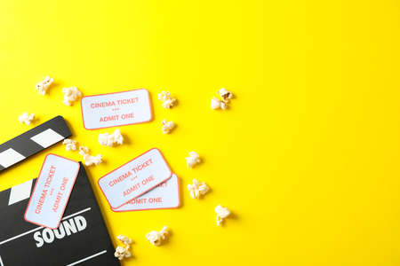 Flat lay composition with clapperboard, popcorn and tickets on yellow backgroundの写真素材