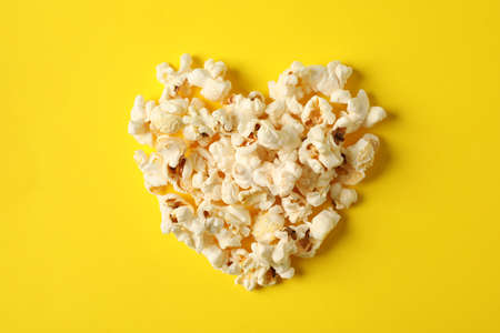 Flat lay composition with popcorn heart on yellow background, space for textの写真素材