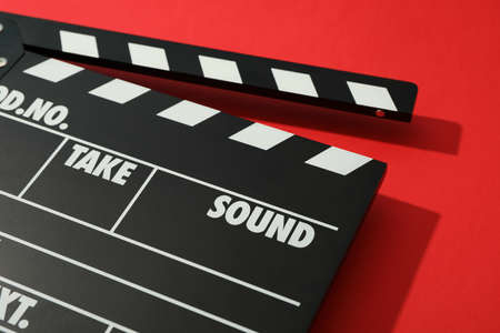 Black clapperboard on red background, space for text