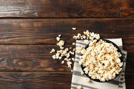 Towel and bowl with popcorn on wooden background, copy spaceの写真素材