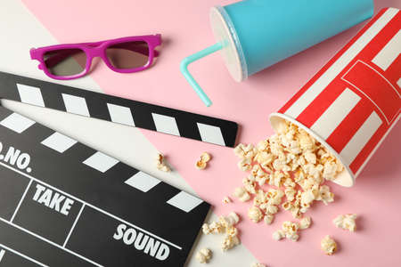 Bucket with popcorn, clapperboard, drink and 3d glasses on two tone backgroundの写真素材