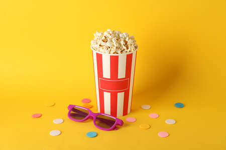 Striped bucket with popcorn and 3d glasses on yellow background, copy spaceの写真素材