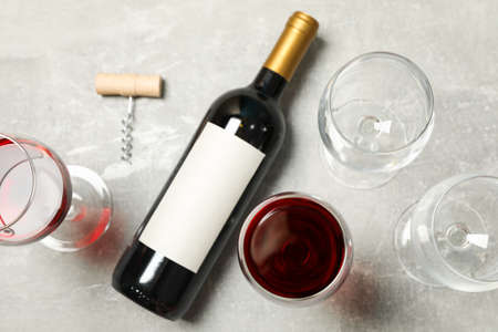 Flat lay composition with bottle and glasses of wine, corkscrew on grey background, copy space