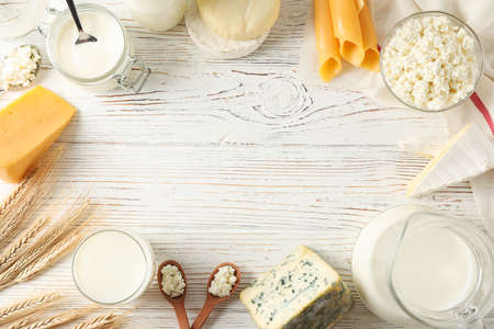 Flat lay. Different dairy products on white wooden background, copy space