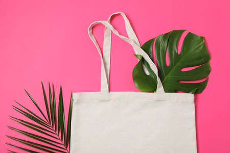 Eco bag and palm leaves on color background, top viewの写真素材