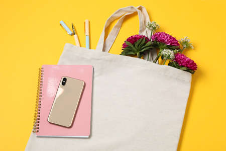 Eco bag, phone, stationery, allium and chrysanthemum on color background, space for textの写真素材