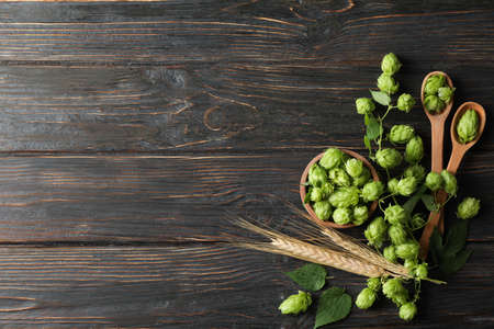 Wooden bowl and spoons with hop and spikelets on wood background, copy spaceの写真素材