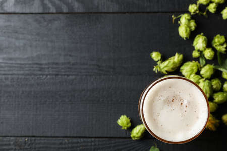 Glass of beer and hop cones on wooden background, top viewの写真素材