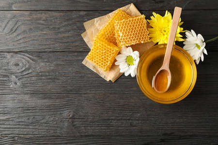 Bowl with honey, honeycombs and flowers on wooden background, copy spaceの写真素材