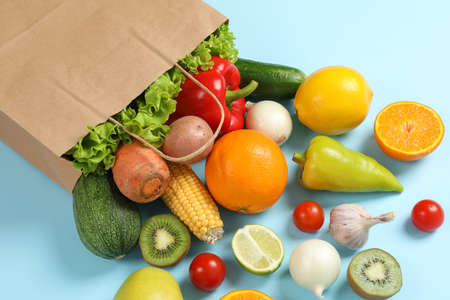 Paper bag, vegetables and fruits on blue background, space for textの写真素材