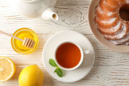 Cup of tea, lemon, mint, honey, dipper and pie on wooden background, top viewの写真素材