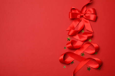 Red ribbon and glitter stars on red background, space for textの写真素材
