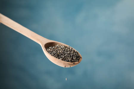 Chia seeds and spoon against blue background, close upの写真素材