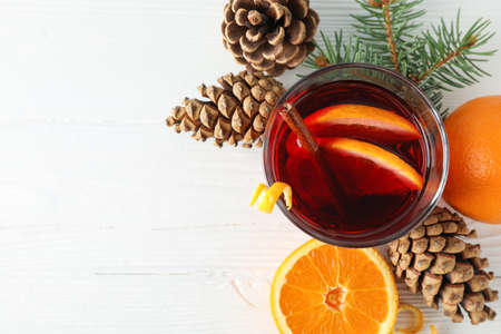 Glass of tasty mulled wine with orange on white wooden background, space for textの写真素材