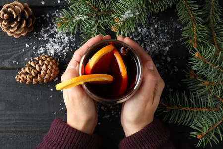 Girl holding glass with mulled wine on decorated wooden background, top viewの写真素材
