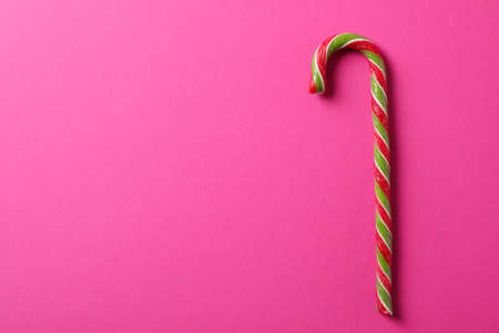 Sweet candy cane on pink background, space for text