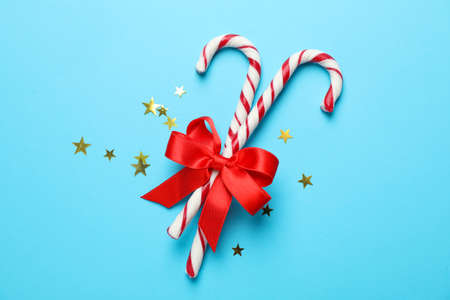 Sweet candy canes and bow on color background, space for textの写真素材