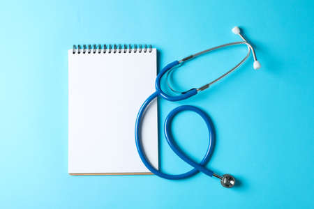 Stethoscope and notepad on a blue background, space for textの写真素材