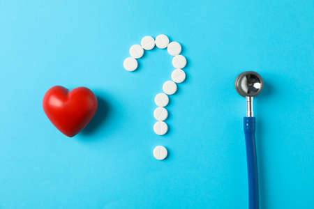Flat lay. Pills, heart and stethoscope on blue background, space for textの写真素材
