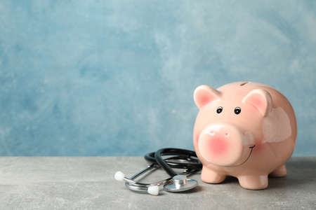 Stethoscope and piggy bank on grey background, space for textの写真素材