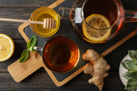 Cup of tea, mint, honey, ginger and teapot on wooden background, top viewの写真素材