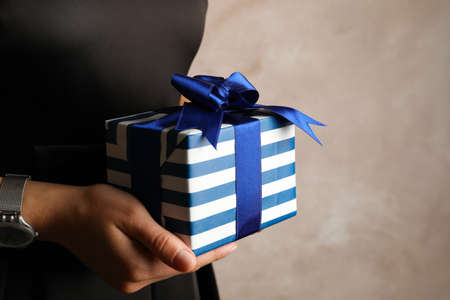 Young woman holding gift box with blue bow, copy space