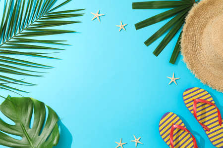 Palm leaves, flip flops, hat and starfishes on blue background, copy spaceの写真素材