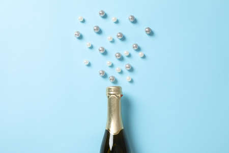 Champagne bottle and glitter on blue background, space for textの写真素材